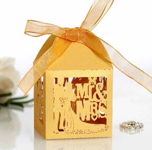 Detail of gold laser-cut wedding candy box with Mr & Mrs silhouette and organza ribbon