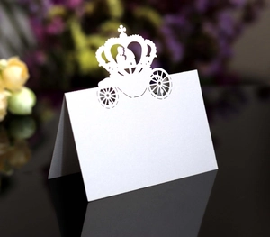Detail of laser-cut crown carriage wedding place card in white textured art paper