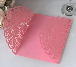 Close-up of pink laser-cut lace invitation cover with elegant hollow patterns