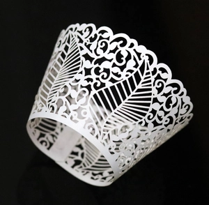 Macro view of white laser-cut vine and leaf patterns on cupcake paper wrapper