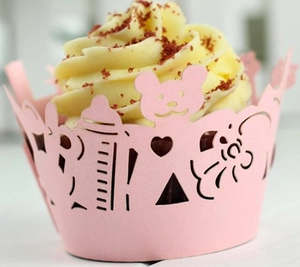 Close-up of laser-cut pink cupcake wrapper with bear and baby bottle hollow design