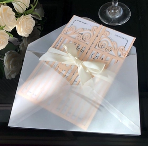 Détail de l'invitation de mariage découpée au laser avec nœud en soie et enveloppe