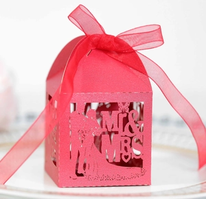 Macro view of laser-cut red wedding favor box with Mr & Mrs silhouette and ribbon