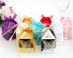 Detail of laser-cut hollow candy boxes with cross motif and ribbon for wedding parties