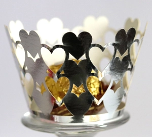 Close-up of laser-cut silver heart cupcake wrappers with golden chocolate balls