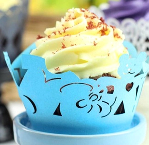 Detail of laser-cut blue cupcake wrappers with heart and bear patterns for birthdays