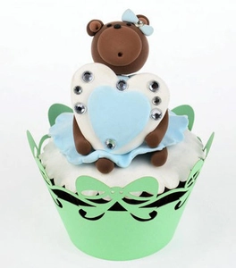 Detail of laser-cut cupcake wrapper with bow pattern and cute brown bear topper