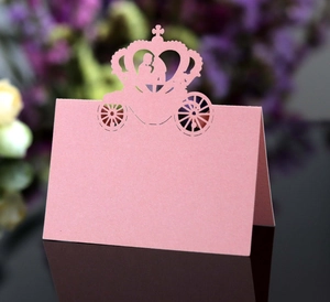 Detailed laser-cut wedding place card with carriage design on reflective surface