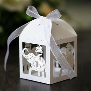 Detail of laser-cut elephant pattern on white pearl paper favor box with organza ribbon