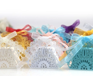 Detailed macro view of laser-cut peacock pattern candy boxes with silk ribbons in various colors