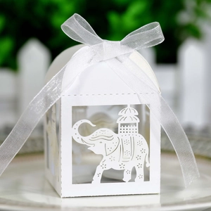 Macro shot of laser-cut elephant pattern on white paper candy box with white silk ribbon