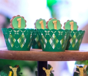 Detail of forest green laser-cut cupcake wrapper with golden number one topper