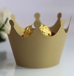 Detail of golden crown laser-cut paper cupcake wrappers with metallic finish and pearly texture