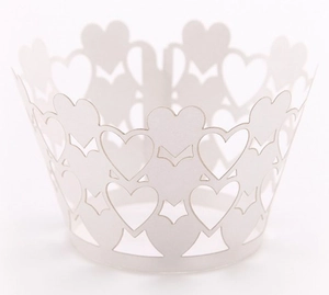 Macro detail of laser-cut white cupcake wrappers with delicate heart and star patterns