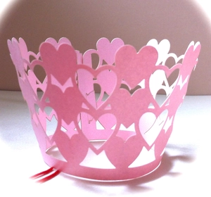 Detail of pink laser-cut cupcake wrappers with intricate hollow heart patterns