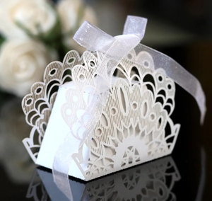 Detailed laser-cut hollow lace design on white wedding favor box with silk ribbon