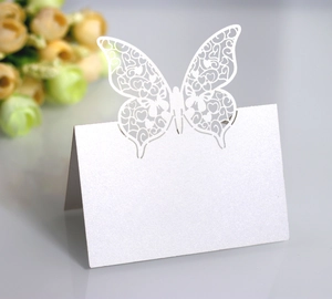 Detail of white butterfly laser-cut place cards with heart pattern for wedding tables