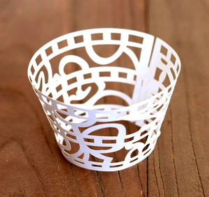 Detailed view of white laser-cut cupcake wrappers with elegant wave hollow patterns