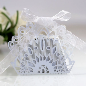 Detailed laser-cut pattern on white wedding favor box with elegant silk ribbon bow