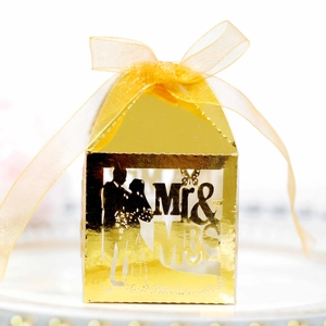 Macro detail of laser-cut gold wedding favor box featuring Mr & Mrs bride and groom silhouette