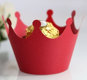 Detail of red crown shaped paper cupcake liner holding a chocolate on white background