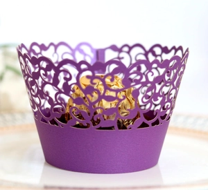Detailed laser-cut purple vine lace cupcake wrapper with golden chocolate on white tray