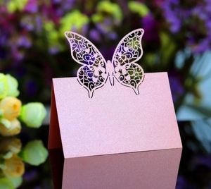 Macro detail of laser-cut pink butterfly place card with pearlescent finish for weddings