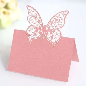 Close-up of laser-cut butterfly place card in pearlescent pink for wedding table decor