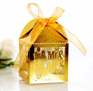 Detail of laser-cut gold wedding favor box with Mr & Mrs silhouette and yellow satin bow