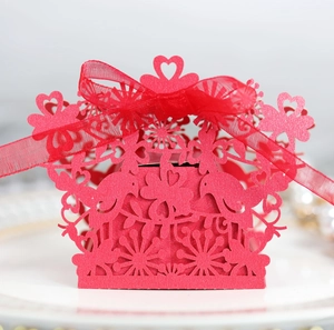 Detail of red laser-cut candy box featuring hollow love birds and organza ribbon