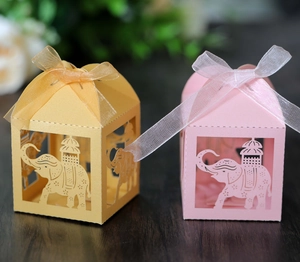 Macro detail of laser-cut elephant favor boxes with ribbons in gold and pink colors