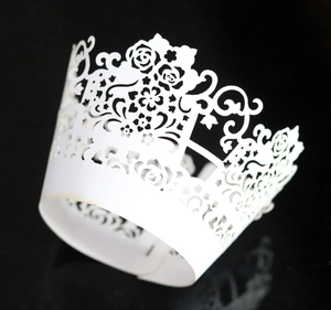 Detailed laser-cut heart and floral vine patterns on white paper cupcake wrappers