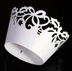 Detail of laser-cut white pearl paper cupcake wrappers with intricate floral patterns