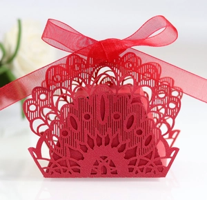 Detail of red laser-cut candy box with peacock petal pattern and red ribbon bow