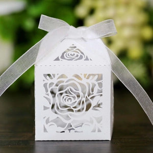 Detail of white laser-cut rose hollow paper gift box with elegant white organza ribbon bow