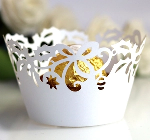 Macro detail of white laser-cut cupcake wrapper with intricate floral and snowflake patterns