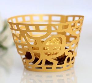 Close-up of golden laser-cut cupcake wrappers with Happy lettering for festive decor