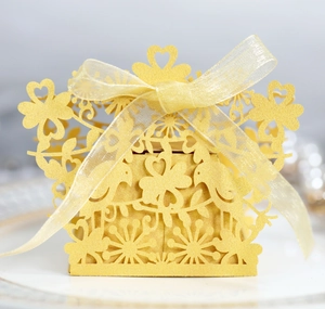 Golden laser-cut wedding candy box with bird and heart patterns and a silk bow ribbon