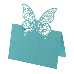 Macro detail of laser-cut butterfly place card in teal blue with intricate heart hollows