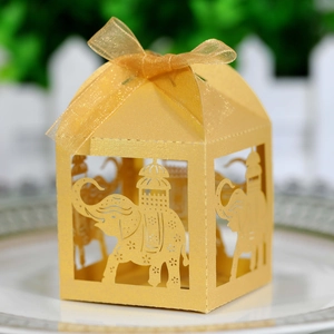 Macro shot of laser-cut elephant favor box in gold pearlescent paper with silk ribbon
