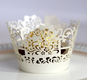 Elegant white laser-cut rose floral cupcake wrapper on white ceramic plate