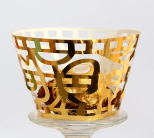 Intricate laser-cut gold cupcake wrapper featuring traditional hollowed pattern for weddings