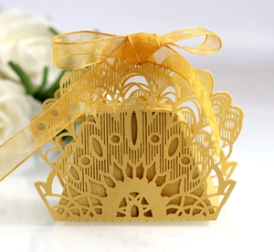 Detailed close-up of golden laser-cut peacock pattern candy box with silk ribbon bow