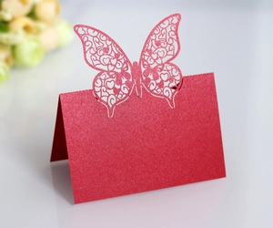 Macro detail of red glitter laser-cut butterfly place card with intricate wing patterns