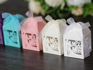 Detail of laser-cut Mr & Mrs wedding favor boxes with elegant ribbons in multiple colors