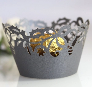 Macro shot of grey laser-cut cupcake wrapper with floral patterns and a gold chocolate