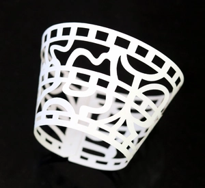 Detailed laser-cut hollow pattern on a white cupcake wrapper for festive party decoration