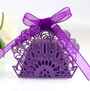 Close-up of laser-cut peacock pattern purple favor box with a satin ribbon bow