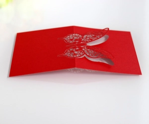 Macro detail of red laser-cut butterfly place card with intricate heart hollow patterns
