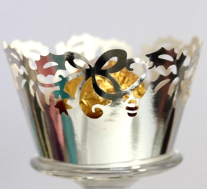 Macro detail of laser-cut silver cupcake wrapper with floral vine patterns